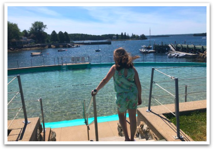 Girl walking down steps to lido pool with ocean in the background.