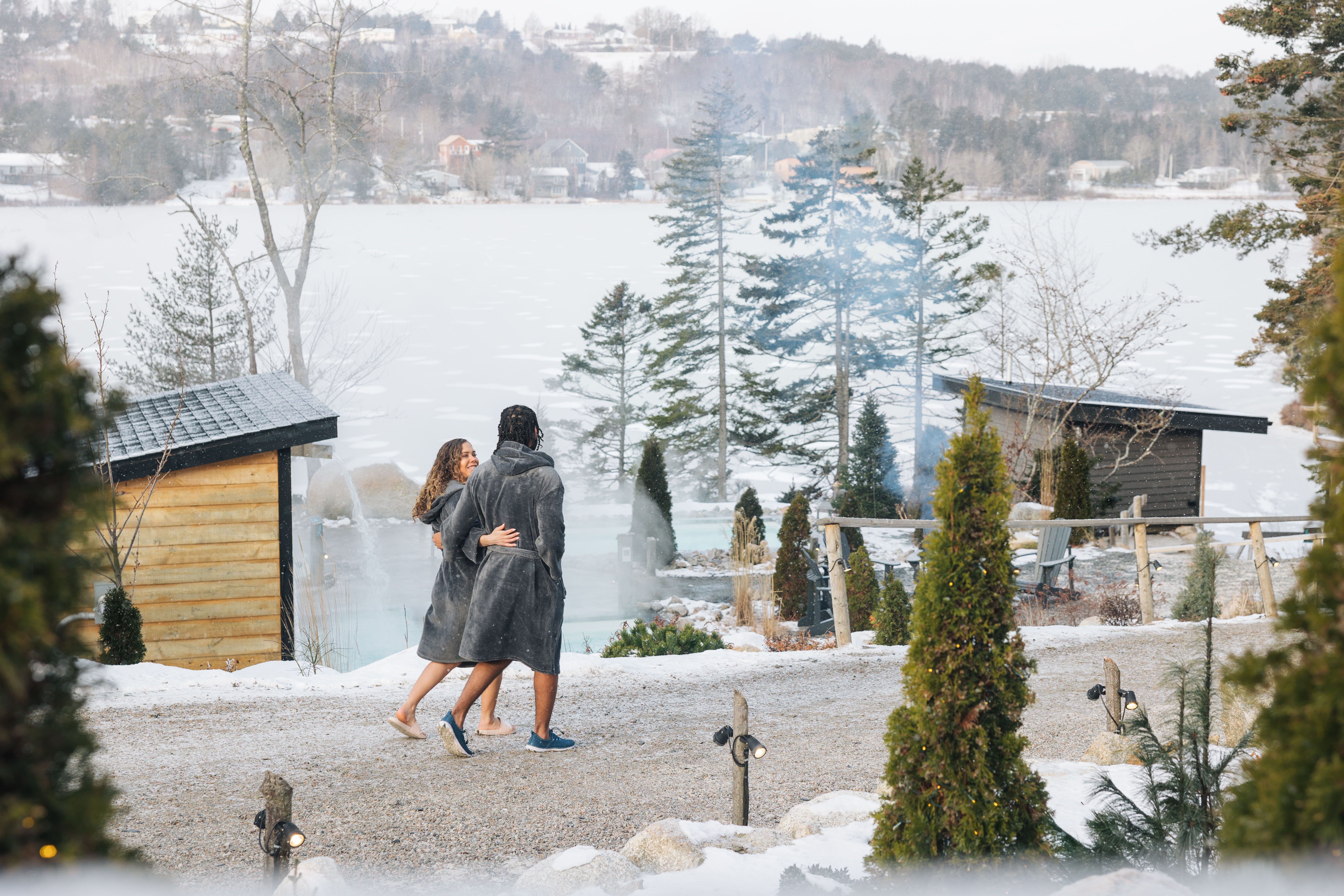 Man and woman walking down a path in winter at sensea wearing grey robes.