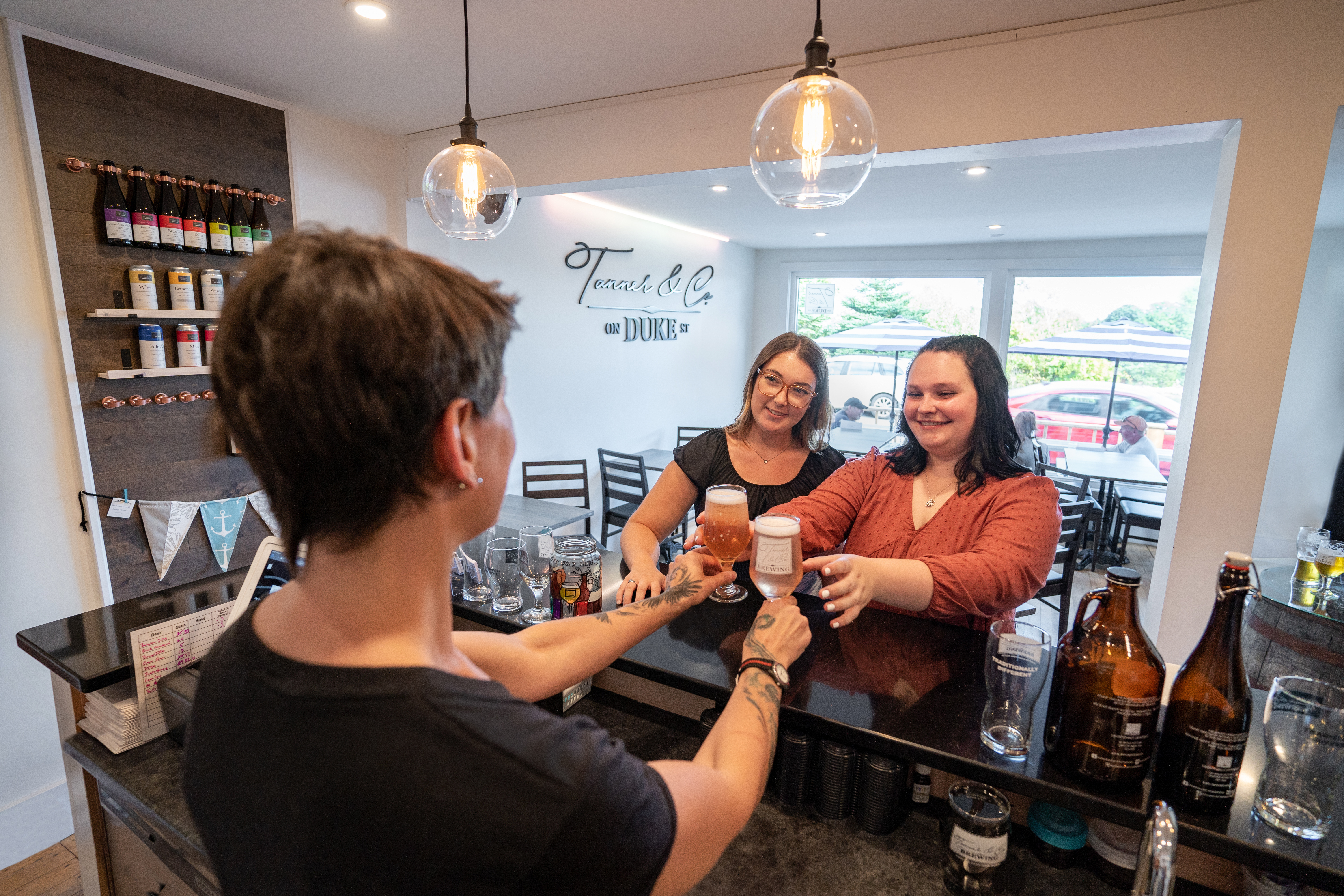 A woman serving two women beer over a counter in Tanner Brewery.