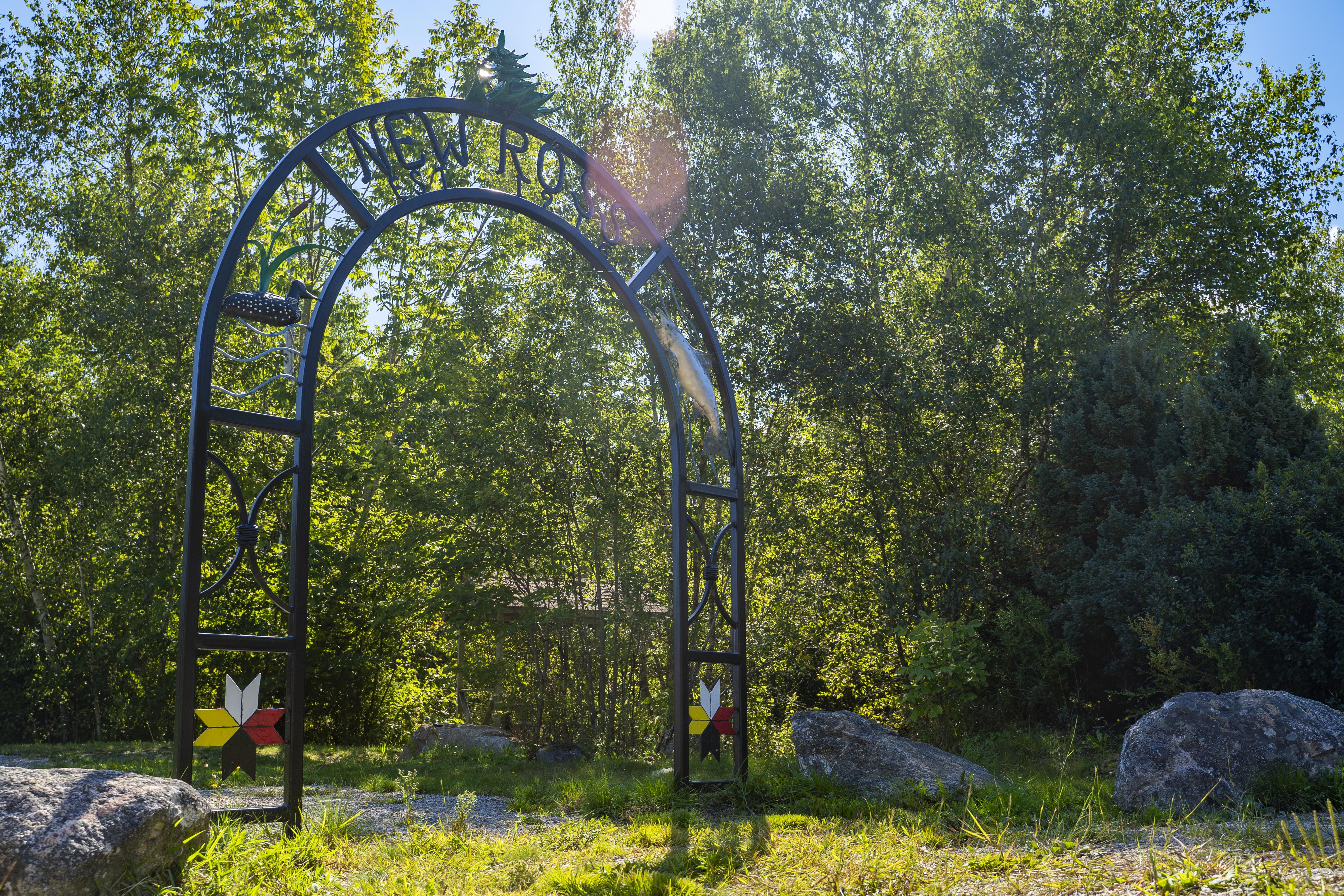 Photo of a large iron archway with the words New Ross at the top, surrounding by trees.