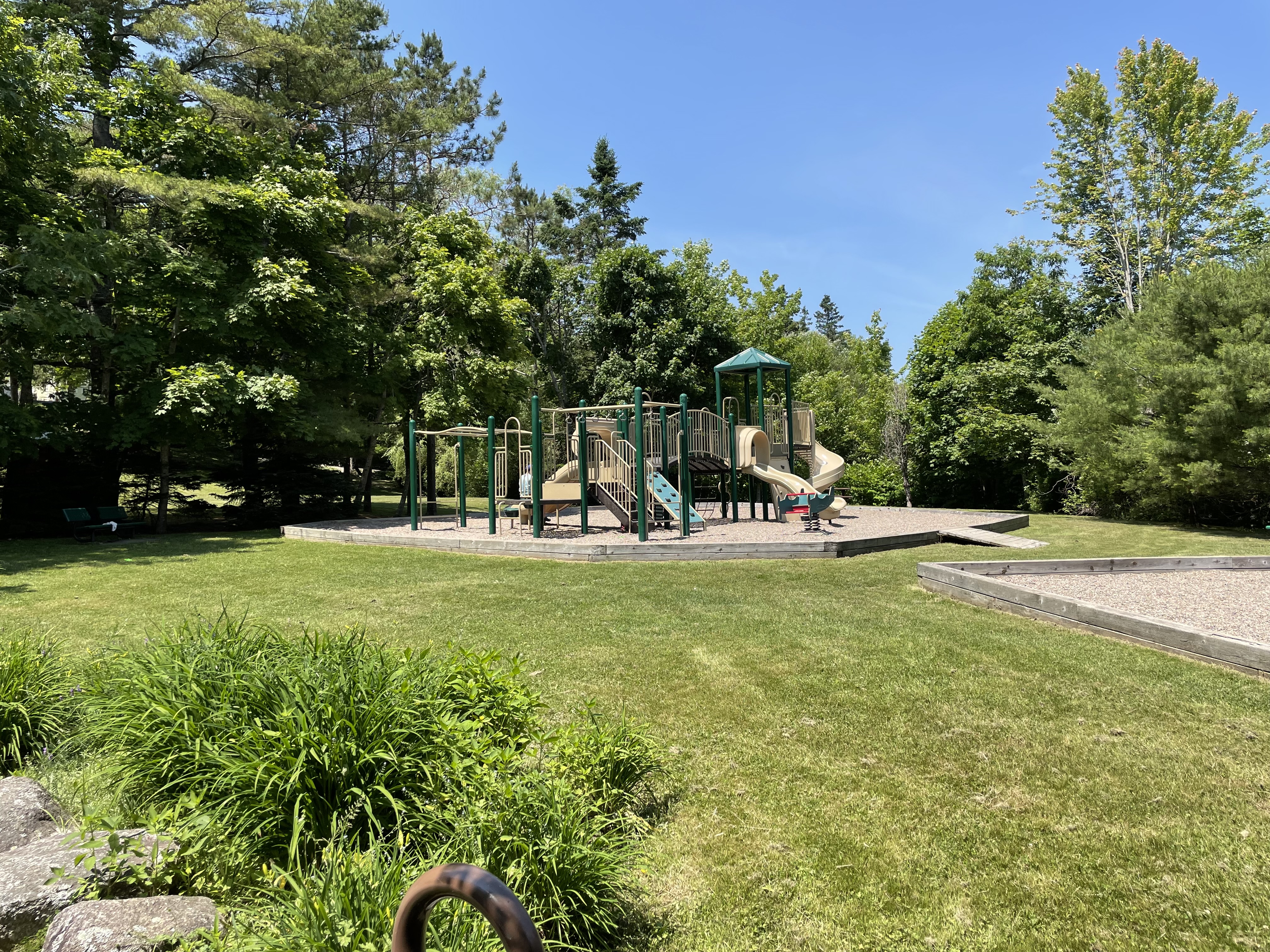 Picture of playground at Lordly Park, green lawn, and slides in the background