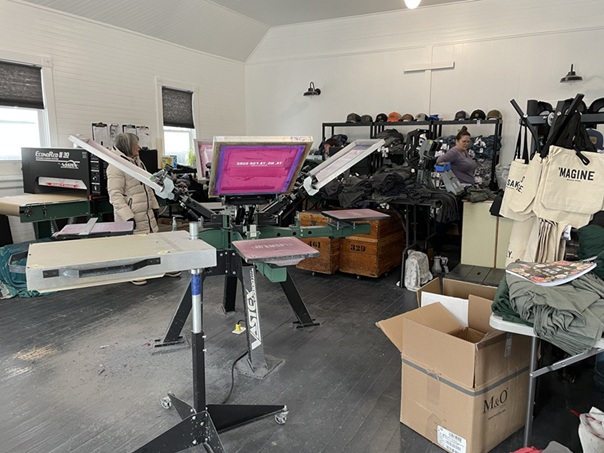 Images of screen printing machine at Noreaster Apparel with bags and t-shirts in the background