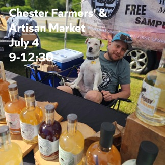 Photo of a man vending at a farmers' market with a dog on his lap