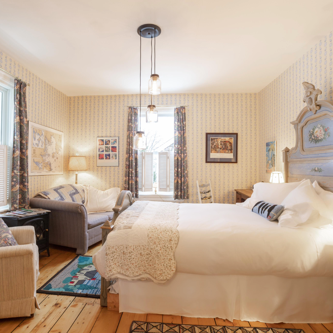 Photo of a room at the Mecklenburg Inn in some white, a double bed and chairs by a window