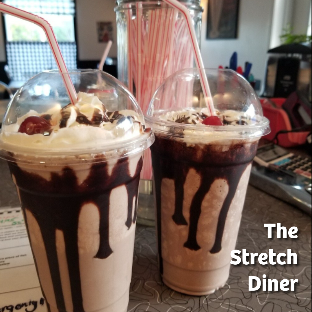 Image show two chocolate milk shakes with chocolate sauce drizzle