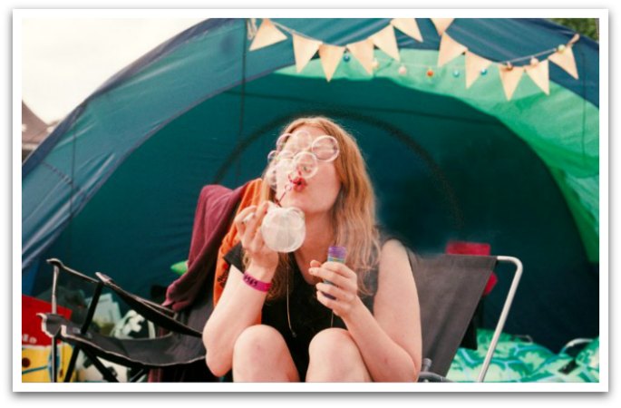 girl blowing bubbles outside of a tent