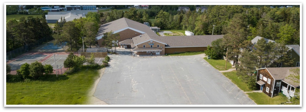 Aerial image of The Park building showing the parking lot, tennis courts, and grass around it.