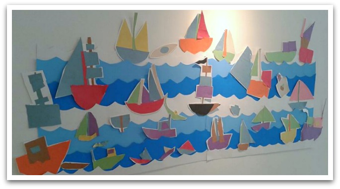Art collage of boats in water displayed on a white wall.