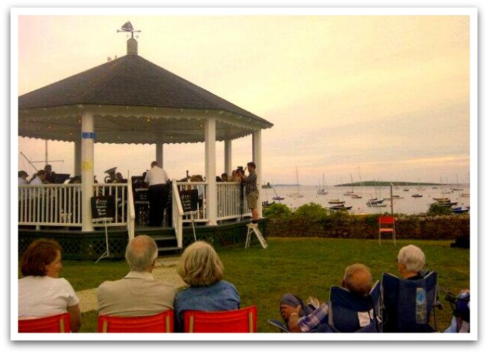 A group watching a band play on the bandstand at sunset.