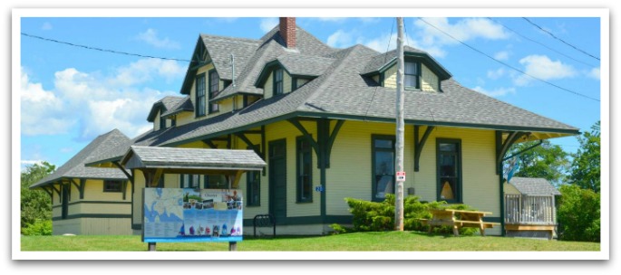 Old, yellow train station building with large map outside.