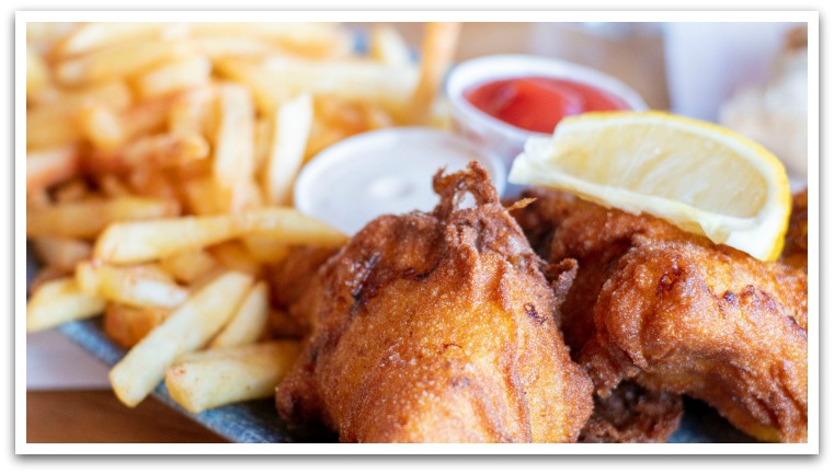 Fish and chips with a slice of lemon and sauces.