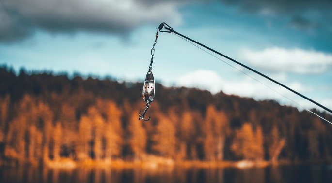 view of hook on a fishing rod with fall coloured trees in the background