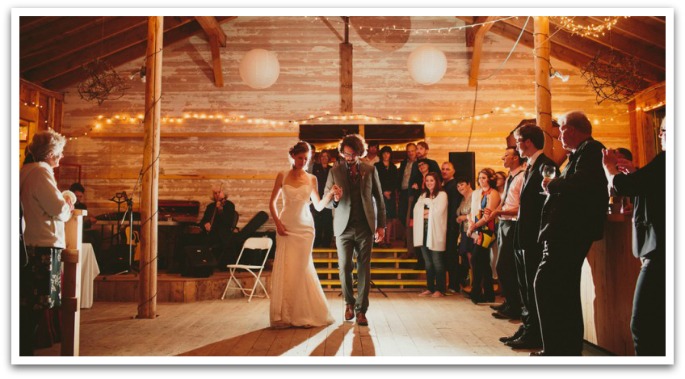Bride and groom in the lower floor of Hubbards Barn dancing under atmospheric lighting with their guests to the right of them watching.