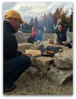 A family grilling hot dogs over an open fire