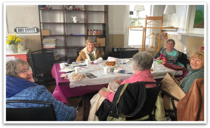 Five women sat around a table smiling at the camera