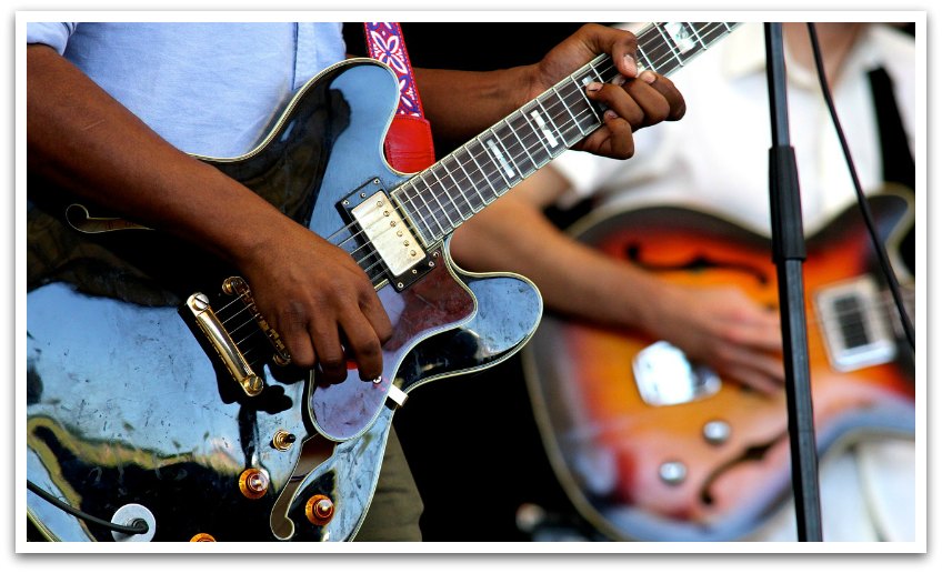 Close up of two men playing electric guitars.