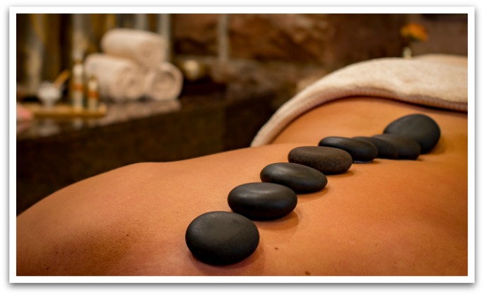Hot stones on a back with rolled up towels in the background.