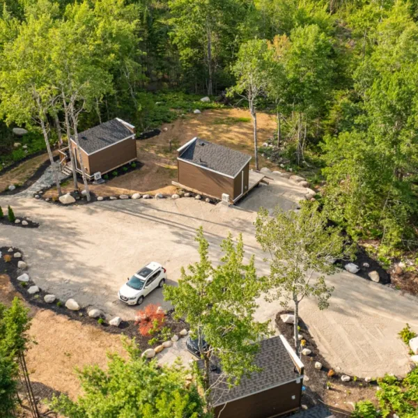 Aerial photo of the Dordean Suites of Chester showing three of their tiny home units with gravel parking surrounding by trees.