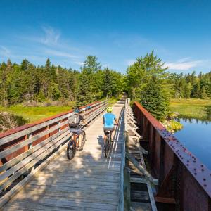 Photo of two people cycling across a bridge over a river along the Run Runners Trail