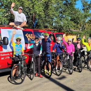 Photo of Free Wheeling Adventure Staff on bikes in colourful clothes with a red van