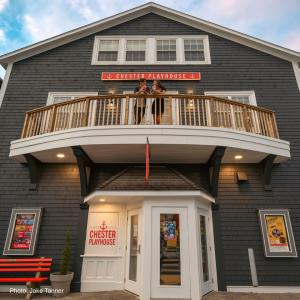 Photo of the main entrance of the chester playhouse with two people standing on the top balcony