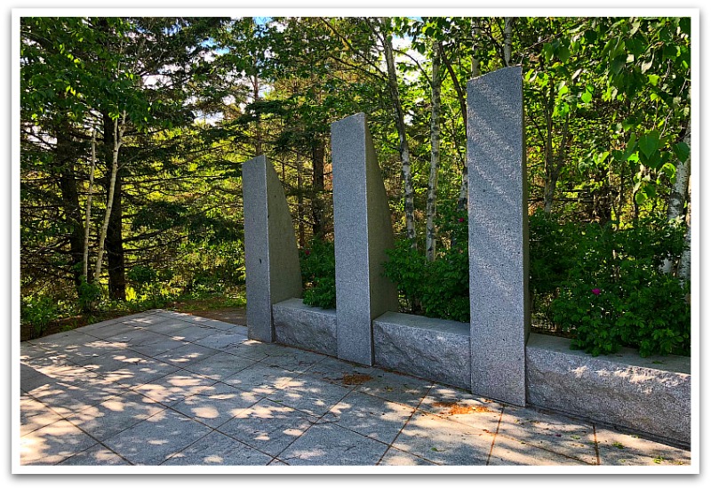 Stone tiles with three small pillars on one side. Surrounded by forestry.