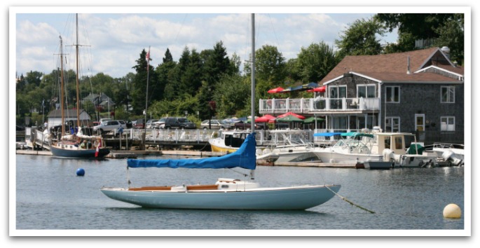 The Rope Loft Chester exterior. Brown 2 story building on water front with sail boats in the foreground.