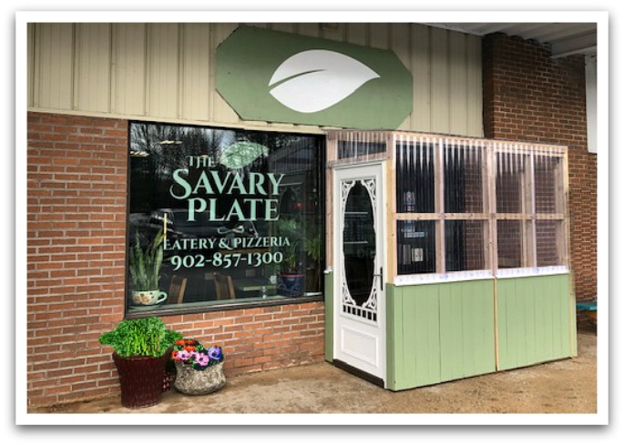Strip mall located Savary Plate exterior. Sign on window reads "The Savary Plate. Eatery and pizzeria. 9028571300."