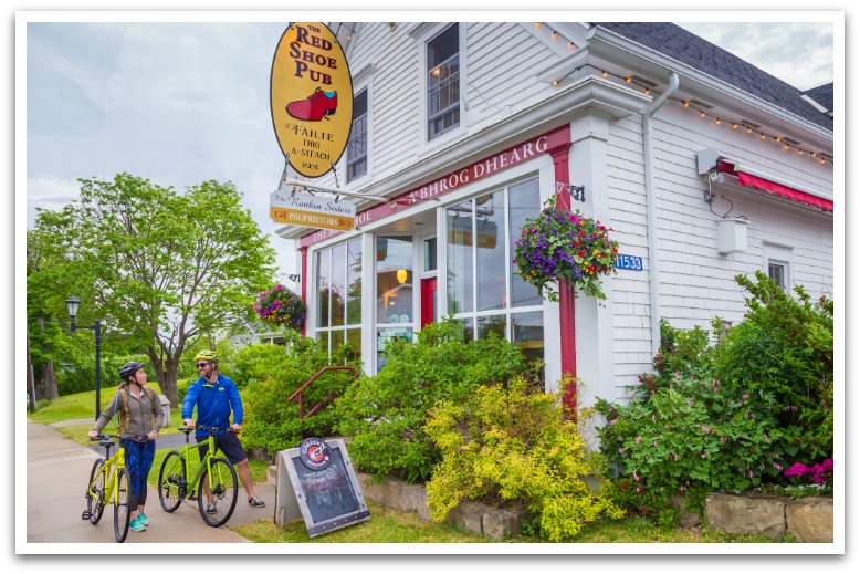 Two cyclists outside a white building with a sign reading "the Red Shoe Pub".