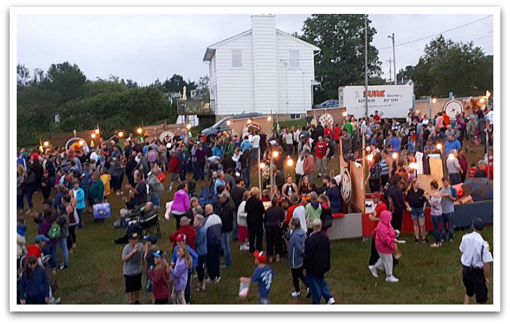 People crowded outside by stalls with glowing lights.